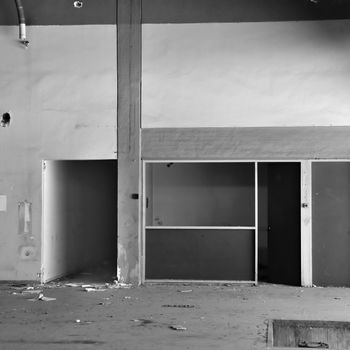 Empty room and concrete wall �n derelict factory interior. Black and white.