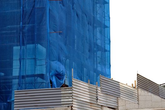 Building covered with construction debris netting. Aluminum fence and scaffold.