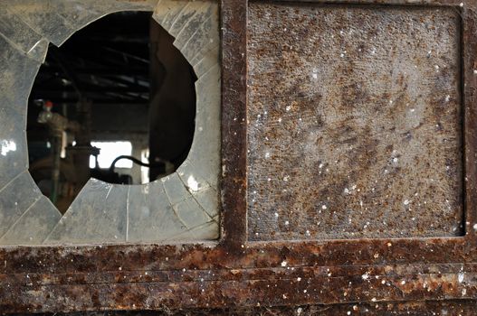 Rusty factory door and smashed glass. Industrial grunge background texture.
