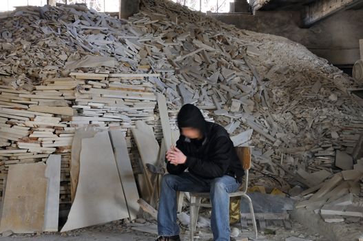 Man sitting next to pile of broken marble in abandoned interior. Motion blur.