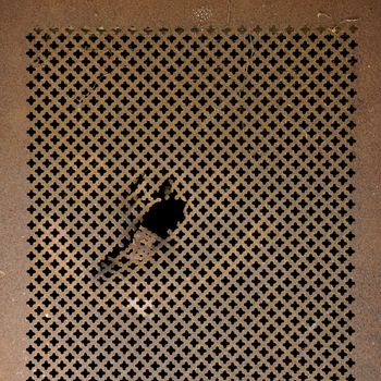Rusty perforated metal surface. Worn iron grille background texture.