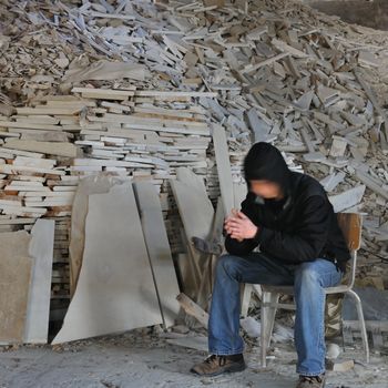 Motion blurred man sitting next to a pile of marble fragments in abandoned interior.