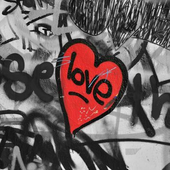 Red painted love heart on graffiti covered black and white wall background. Selective saturation.