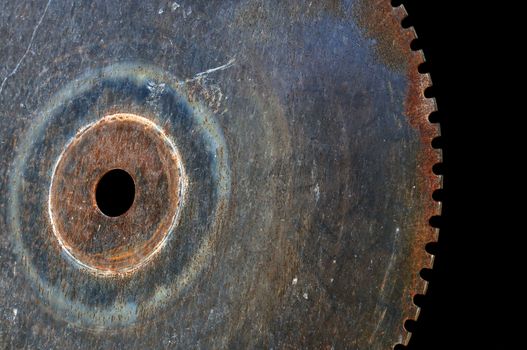 Rusty saw blade cutting wheel. Vintage industrial equipment on black background.