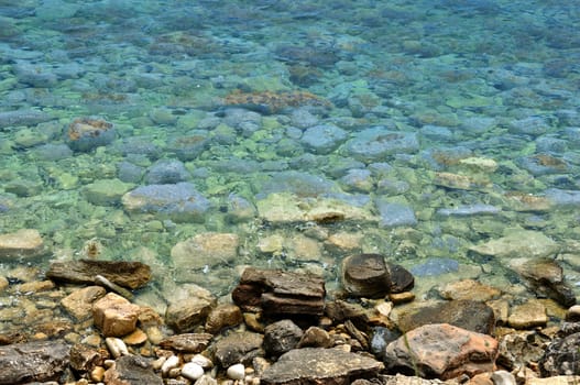 Clear blue sea water and stone beach background.