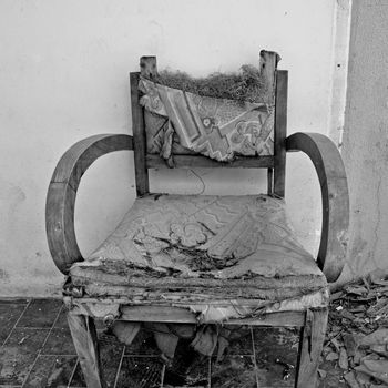 Torn armchair and pile of broken glass. Black and white.