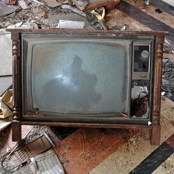 Vintage broken television tv set with wooden frame on dirty floor.