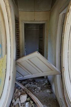 Unhinged door and debris in the corridor of an abandoned house.