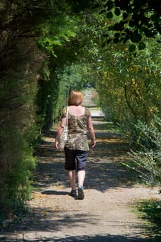 A Woman walking Through a Tree Tunnel