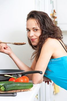 Pretty young woman tasting her cooking