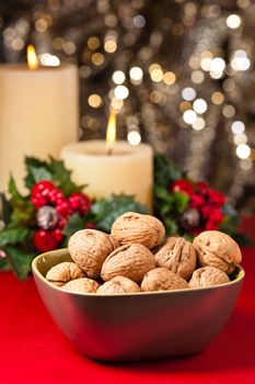 Bowl of walnuts in festive setting in front of a gold glitter background