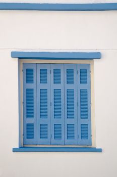 Greek style house in blue and white with wooden blue window shutters