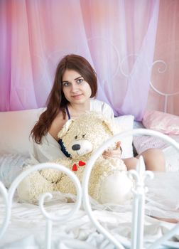 beautiful woman in bed with a white teddy bear