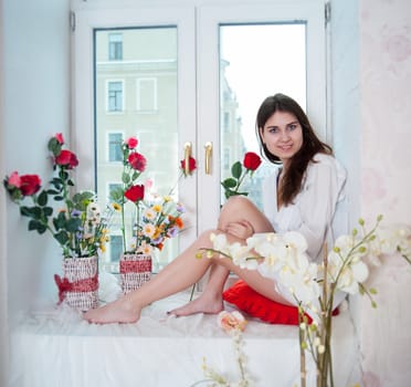 beautiful woman in the flowers on the windowsill