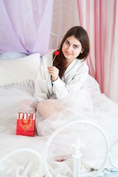 Beautiful woman in bed opening a gift
