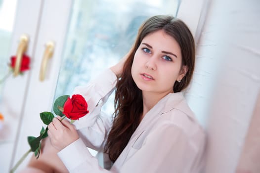 beautiful woman on the windowsill holding a red rose