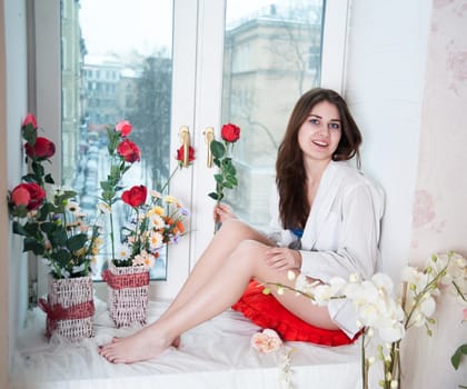 beautiful woman in the flowers on the windowsill