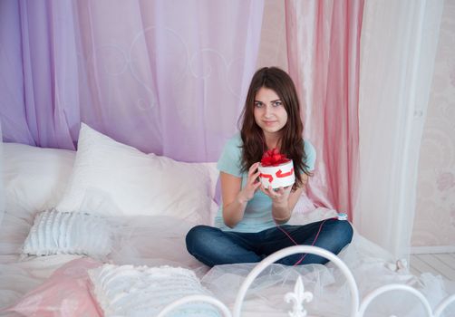 Beautiful woman in bed opening a gift