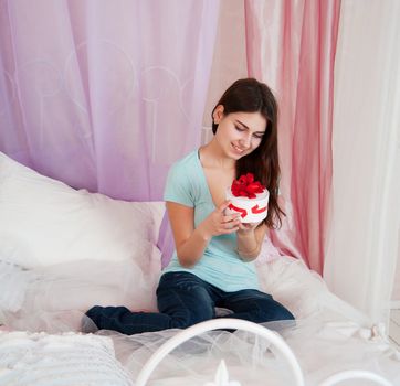 Beautiful woman in bed opening a gift