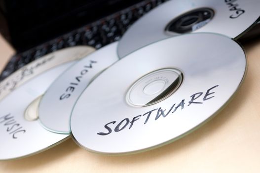 Piracy Concept - Burnt CDs With Illegal Software on Keyboard of Notebook