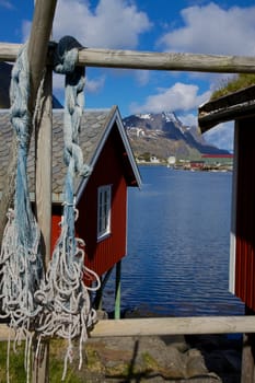 Traditional red fishing rorbu huts by the fjord in town of Reine on Lofoten islands