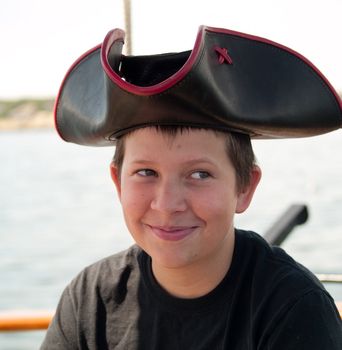 Pre-teen kid in a pirate hat on a boat