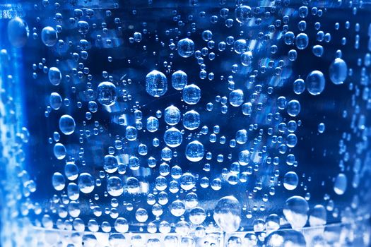 Bubbles in glass of water on a blue background