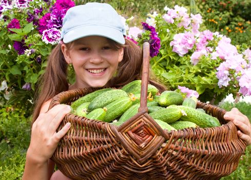 Little girl with the big basket with cucumbers