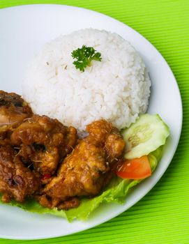 Chicken with rice and vegetables in background