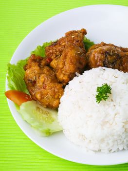 Chicken with rice and vegetables in background