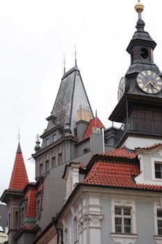 Classical Prague architecture. Gray gothic house with red tiling roof and clock tower, Czech Republic