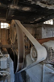 Rusty wheel belt driven machinery in abandoned factory. Industrial interior.