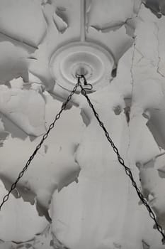Rusty chains and chipped paint white ceiling texture in abandoned interior.