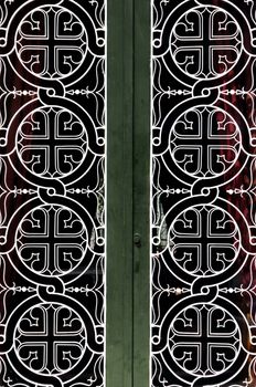 Tangled circles and cross christian religious icon pattern detail on iron church door.