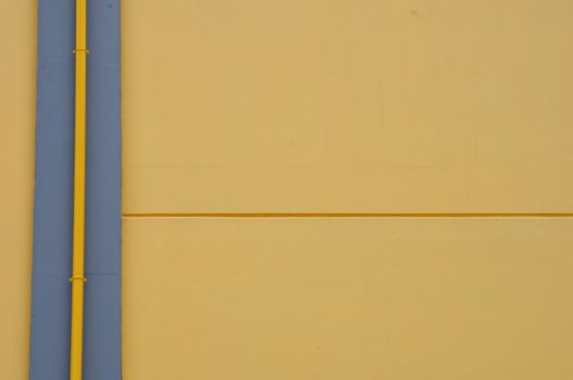 Yellow wall and drain pipe background. Abstract architectural detail.