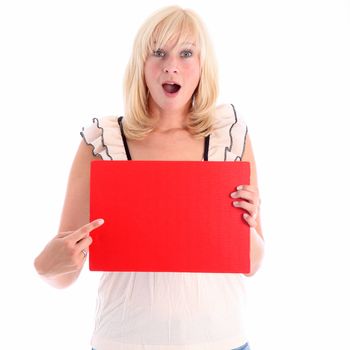 Excited attractive blonde woman with her mouth open in awe pointing to a blank red sign that she is holding ready for your important text 