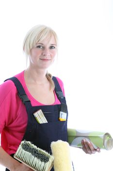 Attractive blonde woman standing holding a roll of wallpaper, brush and roller as she does her wallpapering and redecorating 