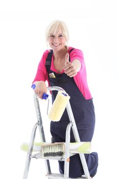Enthusiastic female decorator on a ladder giving a thumbs up gesture of approval and success for her DIY wallpapering project, isolated on white