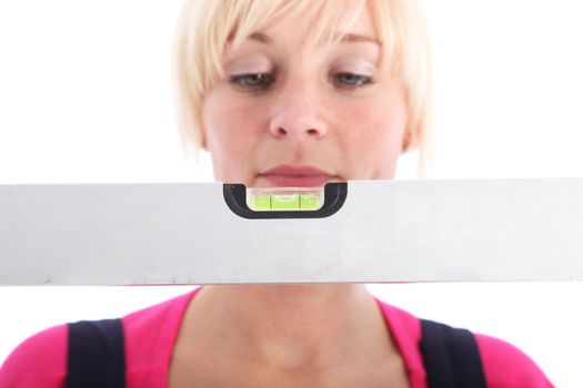 Woman looking at a spirit level to make sure that the construction work she is undertaking is completely level and straight Woman looking at a spirit level to make sure that the construction work she is undertaking is completely level 