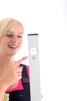 Smiling woman pointing to the bubble in a spirit level with her finger as she checks that her work is level and straight 