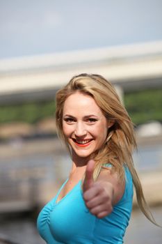 Beautiful busty woman with a lovely smile giving a thumbs up with focus to her face Beautiful busty woman with a lovely smile giving a thumbs up with focus to her face