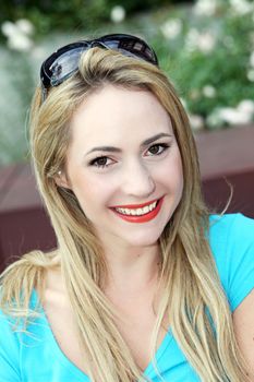 Beautiful trendy young woman wearing red lipstick and sunglasses on her head looking up at the camera with a lovely smile 