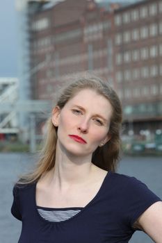 Serious attractive middle-aged woman standing looking straight into the camera in an urban environment