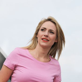 Low angle shot against blue sky of a beautiful woman looking off into the distance as though expecting someone to arrive at any moment Low angle shot of a beautiful woman looking off into the distance as though expecting someone to arrive at any moment