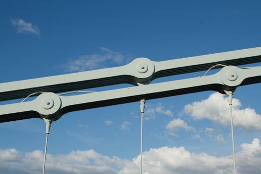 A link section of an industrial chain made of multiple steel plates bolted together, with cable attachements as part of a suspension bridge.