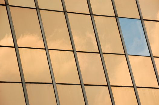 Sky reflected on glass facade panel of a modern building. Abstract background.