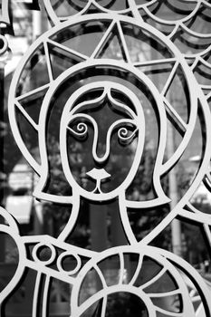 Saint figure on church door detail. Religious icon and light reflections on glass.