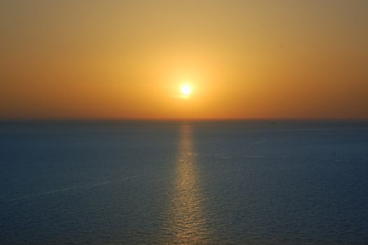 Sunset over water. Deep blue sea and orange colored sky background.