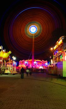 Traditional festival in Prague in night hours. Long exposure turnd people to ghosts and a ferris wheel in the show of neons