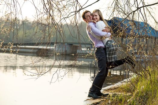 Young couple having fun on river beach in early spring